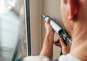 a man caulking a window siding