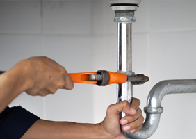 a plumber tightening a pipe